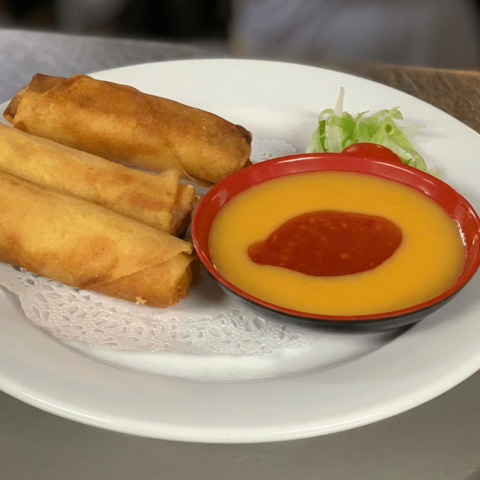 Three golden-fried spring rolls served with yellow dipping sauce, red chili sauce, and lettuce on a white plate.